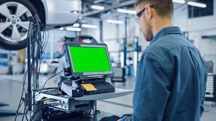 Car Service Mechanic is Running a Diagnostics Software on an Advanced Computer with Green Screen....