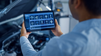 Car Service Manager or Mechanic Uses a Tablet Computer with a Futuristic Interactive Diagnostics...