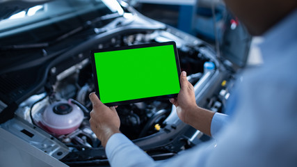 Car Service Manager or Mechanic Uses a Tablet Computer with a Green Screen Mock Up that is Pointed...