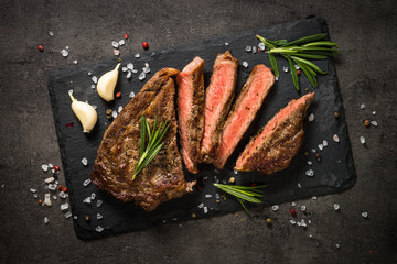 Grilled beef steak on black table.