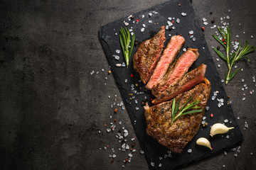 Grilled beef steak on black table. - obrazy, fototapety, plakaty