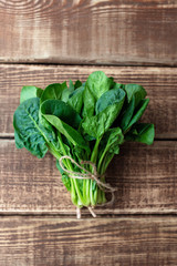 Clean food concept. Leaves of ripe juicy freshly picked organic spinach greens on a wooden background. Healthy detox spring-summer diet. Vegan Raw Food.