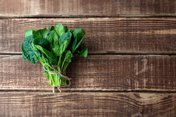Fototapeta premium Clean food concept. Leaves of ripe juicy freshly picked organic spinach greens on a wooden background. Healthy detox spring-summer diet. Vegan Raw Food. Copy space.