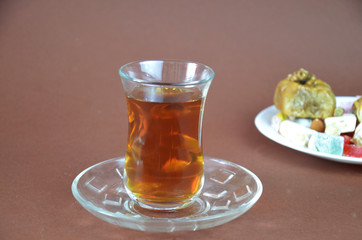 Tasty oriental sweets baklava, turkish delight on a plate on a dark black brown background and glasses of tea