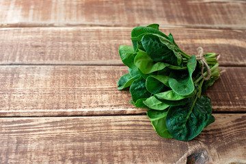 Clean food concept. Leaves of ripe juicy freshly picked organic spinach greens on a wooden background. Healthy detox spring-summer diet. Vegan Raw Food. Copy space.