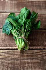 Clean food concept. Leaves of ripe juicy freshly picked organic spinach greens on a wooden background. Healthy detox spring-summer diet. Vegan Raw Food.