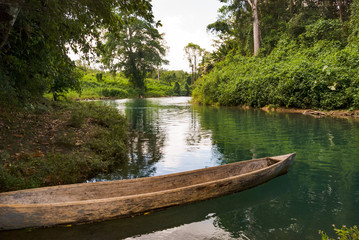 Old style dugout canoe floating on the shore of a tropical river