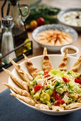 Mediterranean salad with cherry tomatoes, lettuce, grated cheese, and authentic greek cheese.  Greek cuisine salad plating of salad with pita bread. Appetizer photography  on casual dine in table 