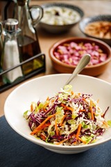 Mediterranean salad with thin sliced carrots, green and purple cabbage.  Greek cuisine salad plating. Appetizer photography  on casual dine in table background.