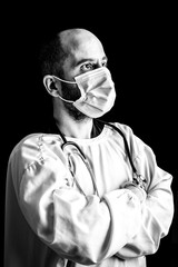 Portrait of a male doctor wearing a mask and a stethoscope against a seemless black background