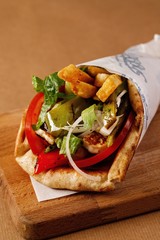 Chicken kontosouvli wrap on wooden chopping board background. Authentic Mediterranean cuisine...
