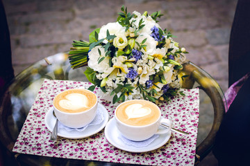 two cups of coffee with a bouquet in the background