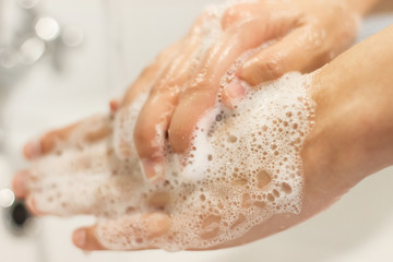 Fototapeta premium Washing hands. Hands washing with antibacterial soap in proper technique on background of flowing water in white bathroom. Prevention coronavirus. Cleaning and disinfecting hands