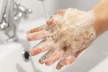 Rubbing fingers, Washing hands with antibacterial soap in proper technique on background of flowing water in white bathroom. Prevention coronavirus. Cleaning and disinfecting