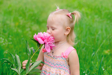 child girl sniffing a peony flower