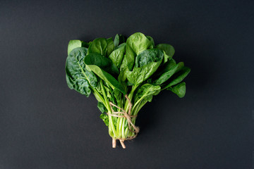 Clean food concept. Bunch of leaves of fresh organic spinach greens on a black background. Healthy...