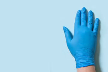 Female hand in sterile latex gloves on a blue background with copy space. Hygiene and virus protection concept.