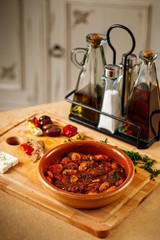 Red sauce with dried tomatoes and herbs. Authentic Mediterranean dish on presentable plating in wooden background.