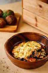 Baked eggplant with mozzarella cheese and herbs in a brown presentable plating, Authentic Mediterranean cuisine photography.