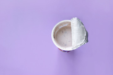 A pink yogurt with strawberry in an open plastic cup on pink background.
