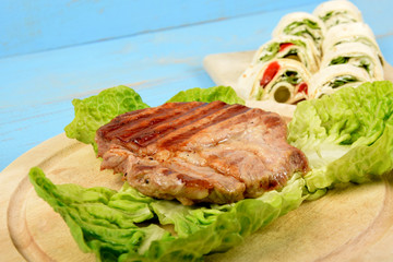 a piece of grilled steak accompanied by wrapped vegetables in a tortilla