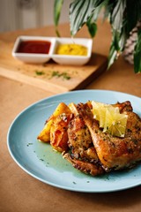 Roasted chicken leg with lemon and herbs. Authentic Mediterranean main course presentable plating on wooden table background.