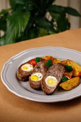 Beef patty with eggs and potato wedges, broccoli and cherry tomatoes on the side. Authentic Mediterranean cuisine photography presentable plating concept.