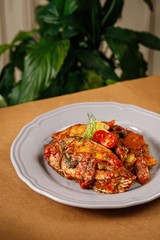 Fish fillet with red sauce on a white plate in wooden background. Authentic Mediterranean cuisine photography.