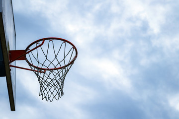 Dark silhouette of street basketball hoop an a cloudy day. Close up of hoop net. Urban youth game