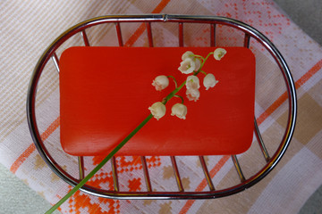 Scented red soap bar on metal soap dish, lily of the valley flower, and cotton towel. Personal hygiene items in the bathroom at home