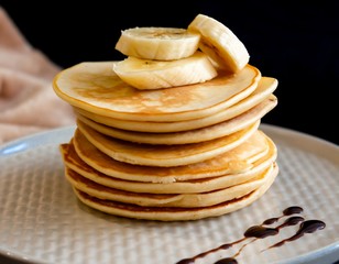 Closeup of delicious pancakes, with banana and chocolate on a dark background. Side view.