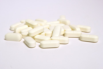 Selective focus on white pills spread on white background with shadow. Global healthcare concept. Antibiotics drug resistance. Antimicrobial pills macro. Pharmaceutical industry.