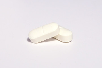 Selective focus on white pills spread on white background with shadow. Global healthcare concept. Antibiotics drug resistance. Antimicrobial pills macro. Pharmaceutical industry.