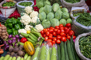 Tomatoes, cucumbers, aubergines, eggplants, cauliflowers and other fresh vegetables on sale in the middle of the street, in an indian food market in Mumbai.