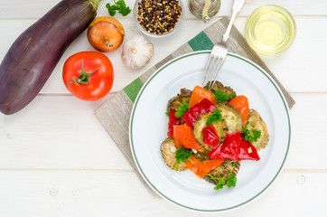 Eggplant, paprika, onion and garlic stew on white wooden table.