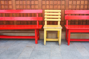 Fototapeta na wymiar Red and Yellow wooden bench chairs in the park.