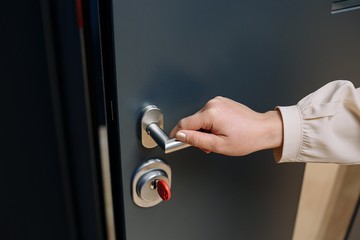 To open the door. Modern door with chrome metal handle and a woman's arm. Elements of interior closeup