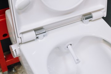 Toilet bowl with manual control bidet. Water sprays from the toilet bowl. A cleansing jet of water designed to cleanse the anus of the user of this bidet-style toilet. - obrazy, fototapety, plakaty