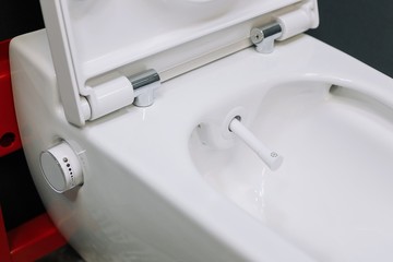 Toilet bowl with manual control bidet. Water sprays from the toilet bowl. A cleansing jet of water designed to cleanse the anus of the user of this bidet-style toilet.