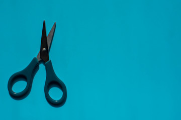 Opened scissors on the blue background for banner or card. Copy space. Top view.