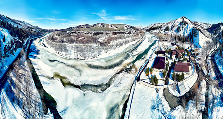 Panoramic aerial view: beautiful spring landscape: the Ulba river in Kazakhstan wakes up from winter sleep - ice drift - snow and ice are melting in the mountains, the bright sun is shining