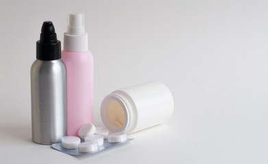 Bottles with tablets in white, pink, gray on a gray background. Copy space