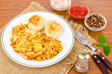 Stewed cabbage, meat cutlets, spices, salt on wooden table.