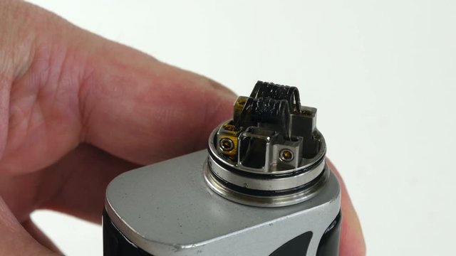 Vaping atomizer with clapton coil is working on a white background.