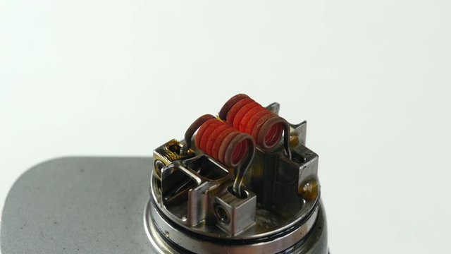 Vaping atomizer with clapton coil is working on a white background.