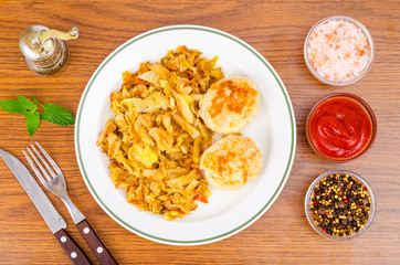 Stewed cabbage, meat cutlets, spices, salt on wooden table.