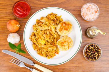 Stewed cabbage, meat cutlets, spices, salt on wooden table.