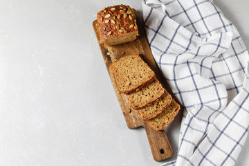Homemade crusty loave of bread with pumpkin seeds on light grey background. Still life concept. Dark mood. Traditional techniques, innovating bread, slow carb baking