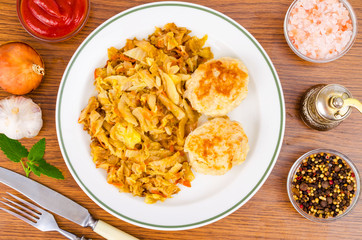 Stewed cabbage, meat cutlets, spices, salt on wooden table.