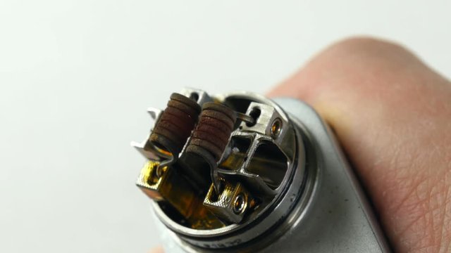 Vaping atomizer with clapton coil is working on a white background.